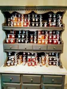 A dresser if filled with small jars of jelly