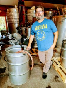 A man in a Nirvana t-shirt poses next to a cask